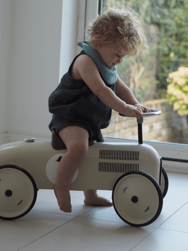Boy model wearing Sage dribble bib riding toy car